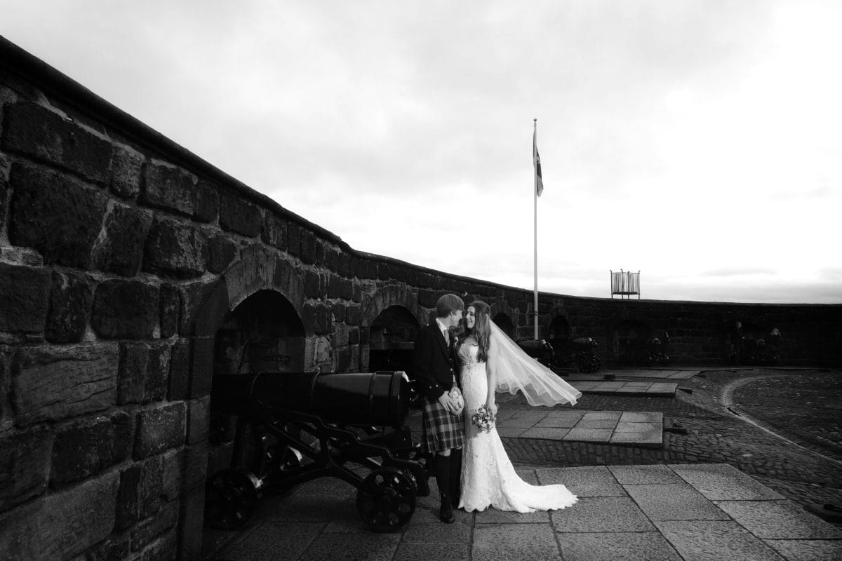 couple in wedding clothes with man in traditional scottish kilt